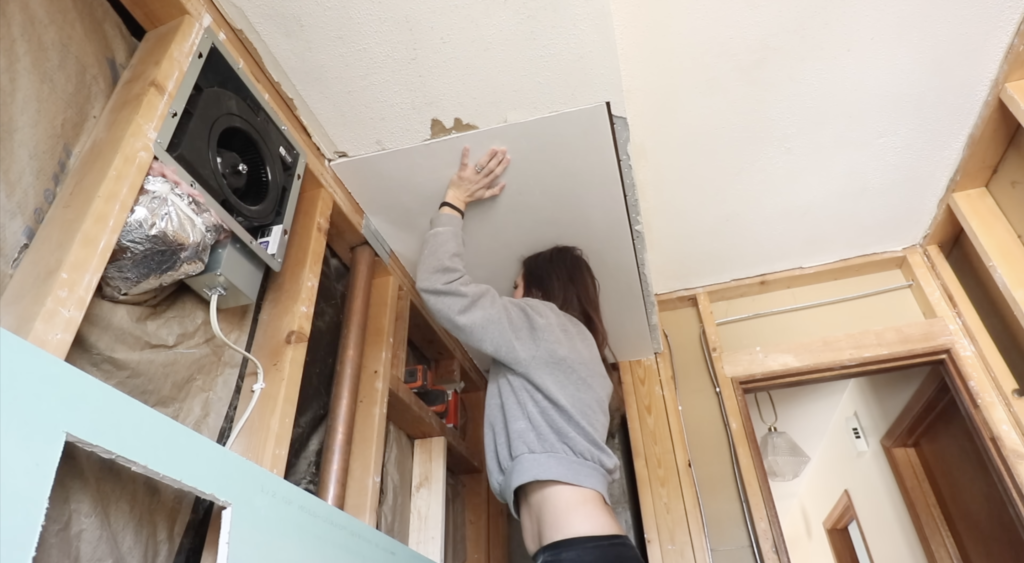 holding the piece of ceiling drywall in place. 